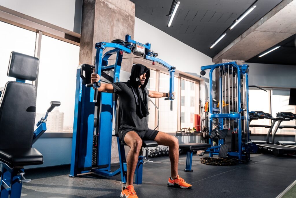 Athletic man working out on a chest fly machine in a modern gym in Bahrain.